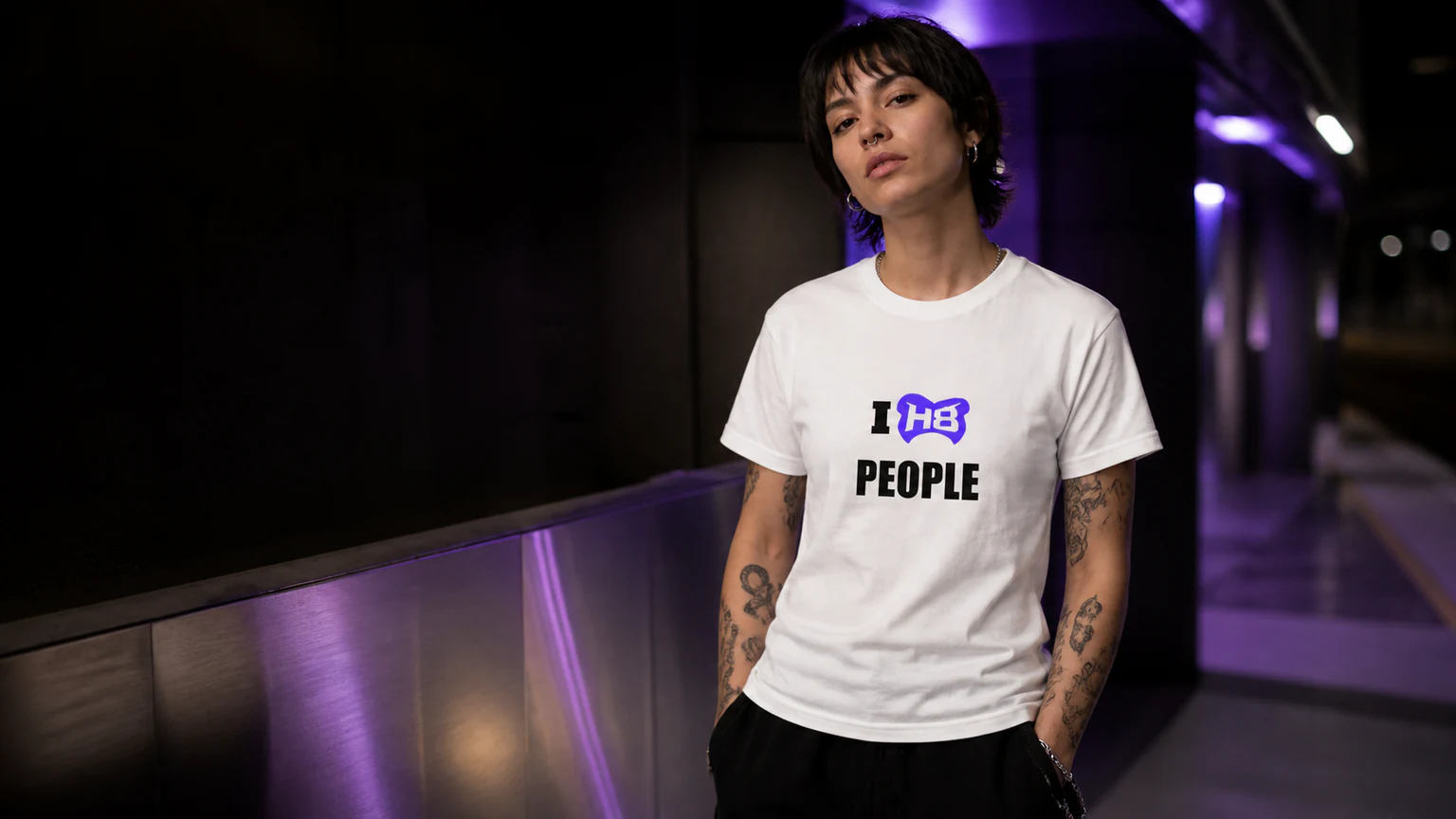 Purple-lit city scene with a model wearing the Transfer Thread I H8 PEOPLE design